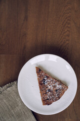 Part of the pie is on a white plate on the table. A piece of lemongrass with blueberries and cranberries without milk and eggs on flaxseed flour. The concept of healthy eating