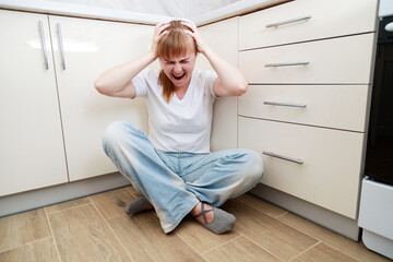 angry, screaming woman sitting on the floor in the kitchen