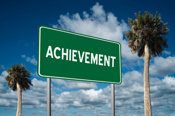 Fototapeta premium Highway sign with the word Achievement on a beautiful blue sky background with palm trees. Motivational concept for finding what we want on the journey of life.