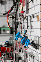 Fototapeta na wymiar Special screwdrivers of different sizes with blue handles are hung on a rack in a bicycle repair shop. The workshop has open cabinets and hanging hooks with various tools and technical fluids