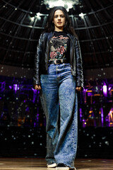 Fancy happy woman posing on a stage of an empty theater lightened by disco globe 