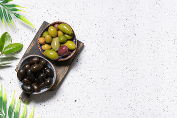 Assortment of tasty olives on the wooden board with allspice and bay tree leaves. Healthy food...