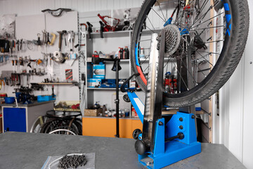 Bicycle wheel holder stand is placed on a table for repairing bicycle equipment in the workshop. Against the background of the wall with tools close-up is a blue bicycle wheel holder. Bicycle service