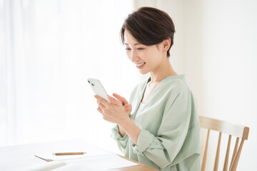 リビングで携帯電話を操作する日本人女性