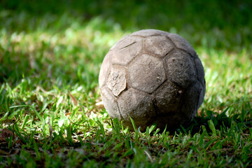 Fototapeta premium The old football was dark gray, laid on a green natural field.
