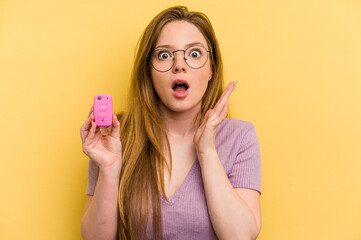 Young caucasian woman holding car keys isolated on yellow background surprised and shocked.