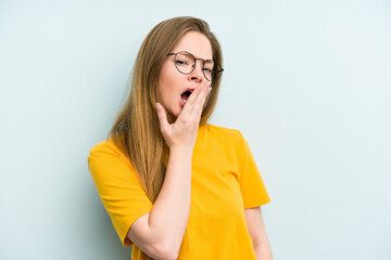 Young caucasian woman isolated on blue background yawning showing a tired gesture covering mouth with hand.