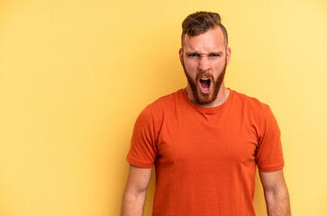 Obraz premium Young caucasian man isolated on yellow background shouting very angry, rage concept, frustrated.