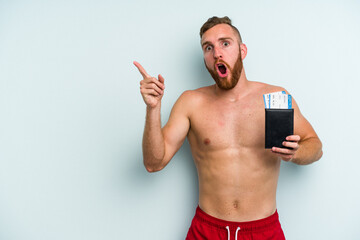 Young caucasian man holding a passport isolated on blue background pointing to the side