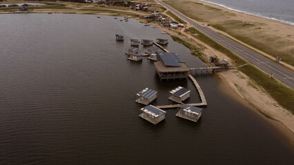 Aerial orbit shot of floating houses in Laguna Garzon,Uruguay with Atlantic Ocean and sandy beach...