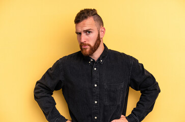 Obraz premium Young caucasian man isolated on yellow background frowning face in displeasure, keeps arms folded.