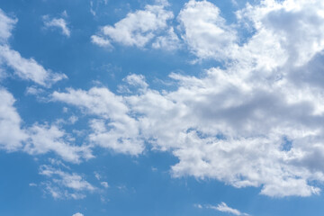 Blue sky background with white fluffy cumulus clouds. Panorama of white fluffy clouds in the blue sky. Beautiful vast blue sky with amazing scattered cumulus clouds.