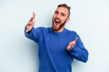 Fototapeta premium Young caucasian man isolated on blue background feels confident giving a hug to the camera.