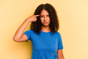 Young Brazilian woman isolated on yellow background pointing temple with finger, thinking, focused on a task.