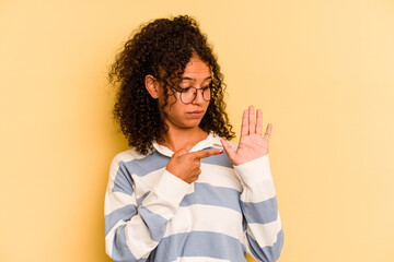 Young Brazilian woman isolated on yellow background smiling cheerful showing number five with fingers.