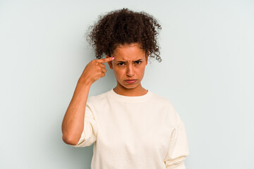 Young Brazilian woman isolated on blue background pointing temple with finger, thinking, focused on a task.