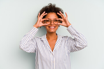 Young Brazilian woman isolated on blue background showing okay sign over eyes