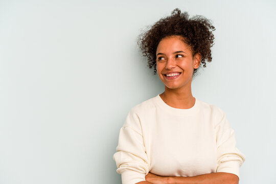 Young Brazilian woman isolated on blue background smiling confident with crossed arms.