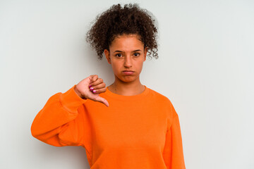 Young Brazilian woman isolated on blue background showing a dislike gesture, thumbs down....