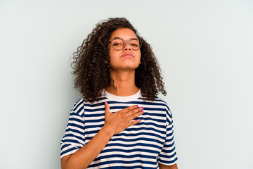 Young Brazilian woman isolated on blue background taking an oath, putting hand on chest.