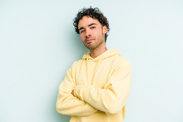 Young caucasian man isolated on blue background suspicious, uncertain, examining you.