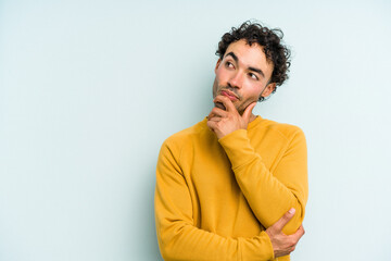 Fototapeta na wymiar Young caucasian man isolated on blue background relaxed thinking about something looking at a copy space.