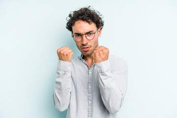 Young caucasian man isolated on blue background upset screaming with tense hands.