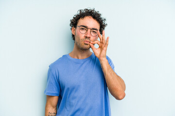 Young caucasian man isolated on blue background with fingers on lips keeping a secret.