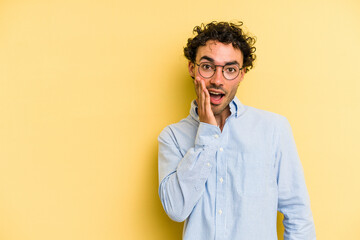 Young caucasian man isolated on yellow background shouts loud, keeps eyes opened and hands tense.