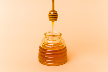 Jar of honey isolated on beige background