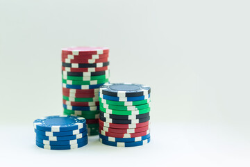 Stacks of poker chips including red, black, white, green and blue on a white background