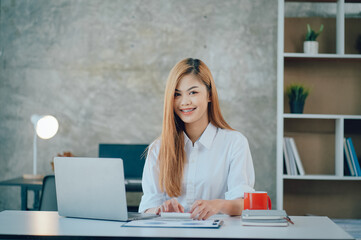 Portrait of smiling pretty young business woman sitting on workplace