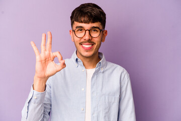 Naklejka premium Young caucasian man isolated on purple background cheerful and confident showing ok gesture.