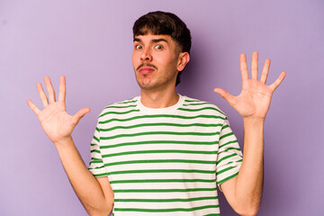 Naklejka premium Young caucasian man isolated on purple background being shocked due to an imminent danger