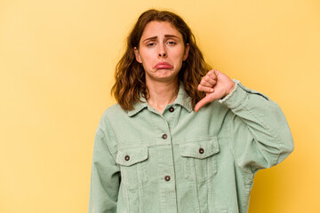 Young caucasian woman isolated on yellow background showing a dislike gesture, thumbs down. Disagreement concept.