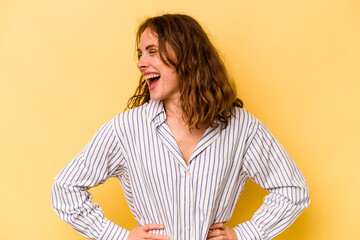 Young caucasian woman isolated on yellow background laughs happily and has fun keeping hands on...