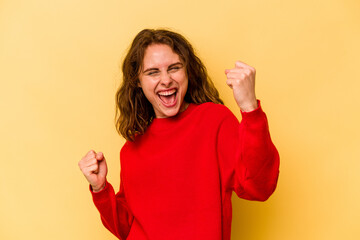 Young caucasian woman isolated on yellow background cheering carefree and excited. Victory concept.