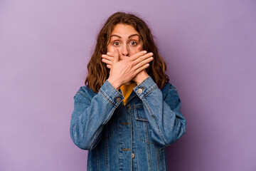 Young caucasian woman isolated on purple background shocked covering mouth with hands.