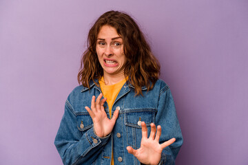 Young caucasian woman isolated on purple background rejecting someone showing a gesture of disgust.