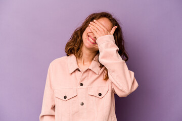 Young caucasian woman isolated on purple background laughs joyfully keeping hands on head. Happiness concept.