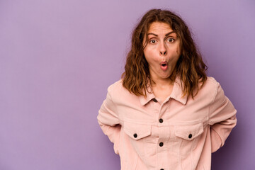 Young caucasian woman isolated on purple background being shocked because of something she has seen.
