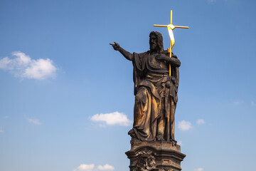 Saint John Baptist statue at the Charles bridge is under blue sky