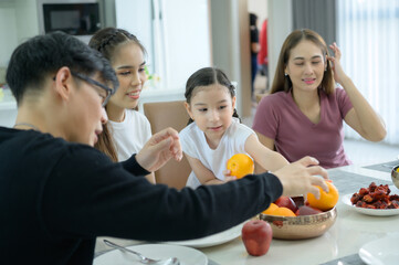 Asian family They are having breakfast together happily in the dining room of the house.