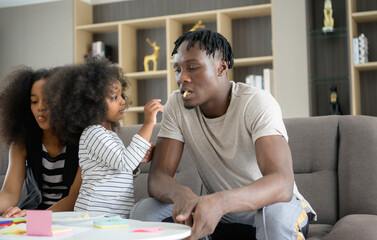 Asian-African American family relaxing, chatting, painting and having fun on vacation in the living room of the house