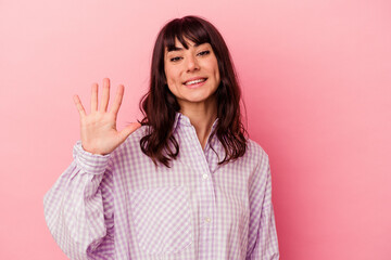 Fototapeta premium Young caucasian woman isolated on pink background smiling cheerful showing number five with fingers.