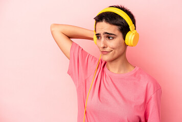 Young caucasian woman listening to music isolated on pink background touching back of head, thinking and making a choice.