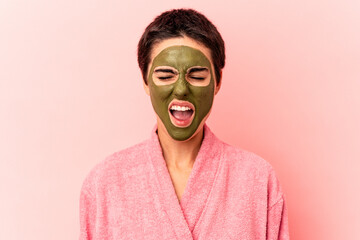 Young caucasian woman wearing a face mask isolated on pink background screaming very angry and aggressive.