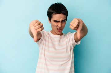 Young caucasian woman isolated on blue background showing thumb down and expressing dislike.