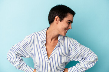 Young caucasian woman isolated on blue background laughs happily and has fun keeping hands on stomach.