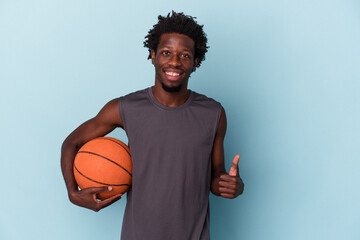 Young african american man playing basketball isolated on blue background smiling and raising thumb...